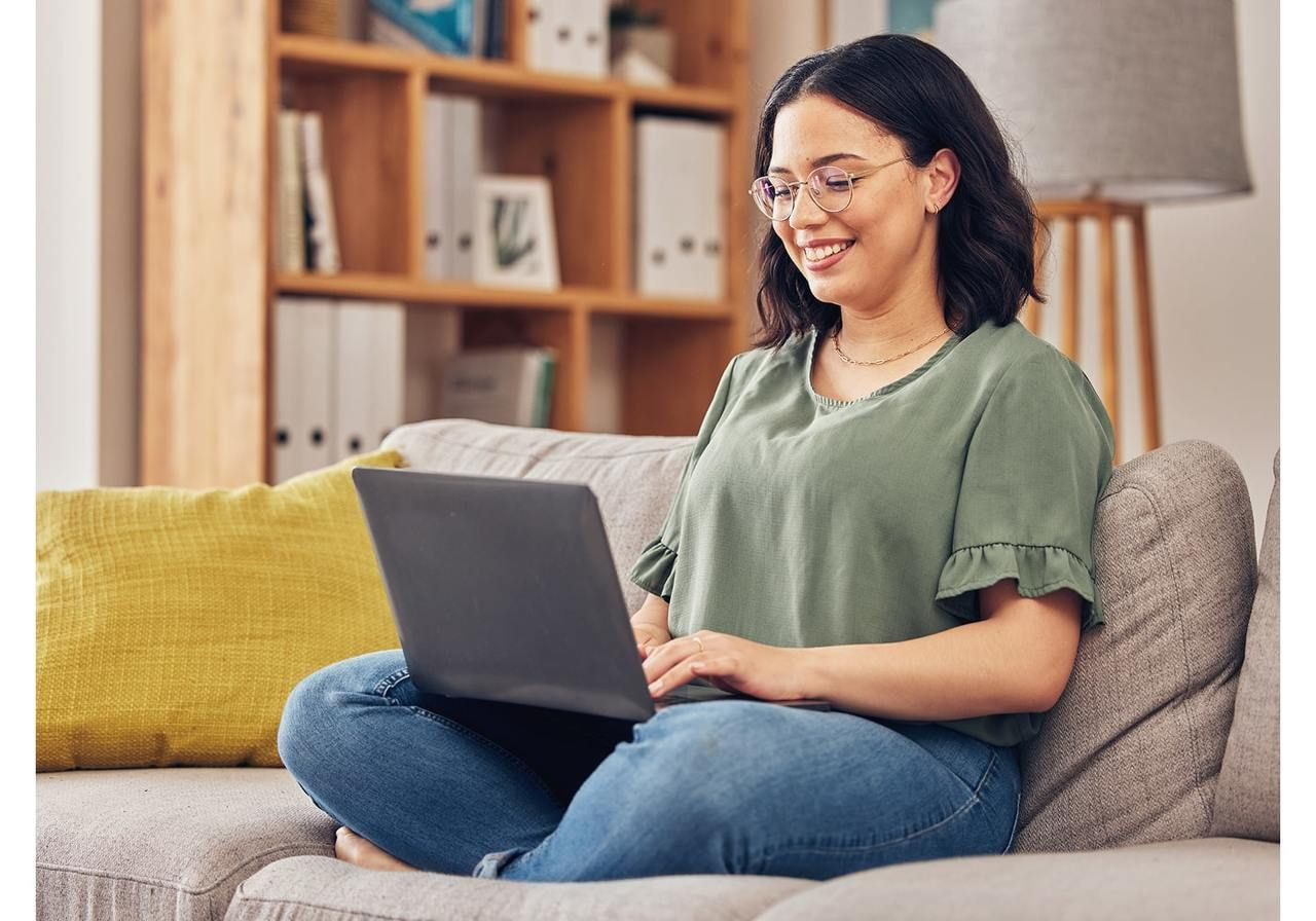 A woman sitting with a laptop on a couch.